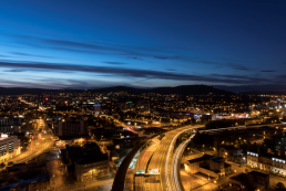 Night time cityscape of Belfast showing roads and motorways, street lights and mountains in the distance